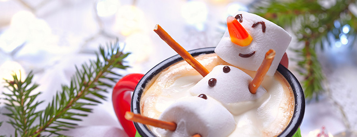 Close up of a marshmallow decorated and shaped as a snowman, floating in a cappuccino